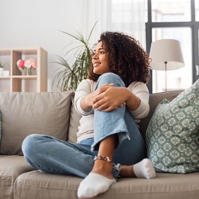 Happy young woman sitting on sofa at home after her eye care treatment